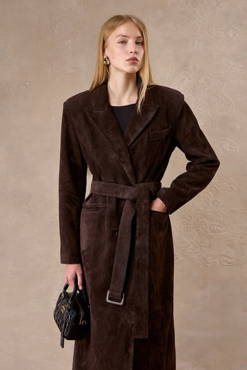Elegantly dressed, a woman models a premium chocolate suede coat featuring wide shoulders and a waist-cinching belt for a graceful look.