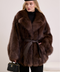 Elegant woman wearing a natural fox fur coat cinched at the waist with a leather belt for a refined, feminine silhouette.