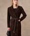 Elegantly dressed, a woman models a premium chocolate suede coat featuring wide shoulders and a waist-cinching belt for a graceful look.