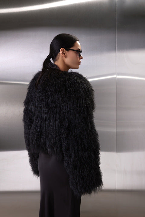 A woman dons the genuine Mongolian Coat, blending plush fur warmth with chic hidden snaps and side pockets for a polished winter look.