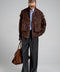 A model wears this dark brown suede jacket, combining trendy style with everyday practicality in a soft, high-quality leather design.