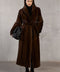 A woman wears a full-length dark brown mink fur coat, radiating elegance and warmth with its rich, velvety texture.