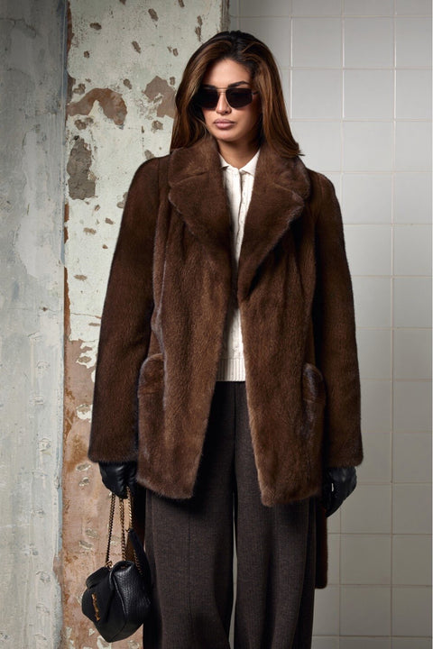 Brown Short mink fur coat model wearing sunglasses in an elegant setting.