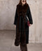 A woman wears an elegant black double-faced cashmere coat with a rich brown fox fur trim, exuding timeless sophistication and grace.