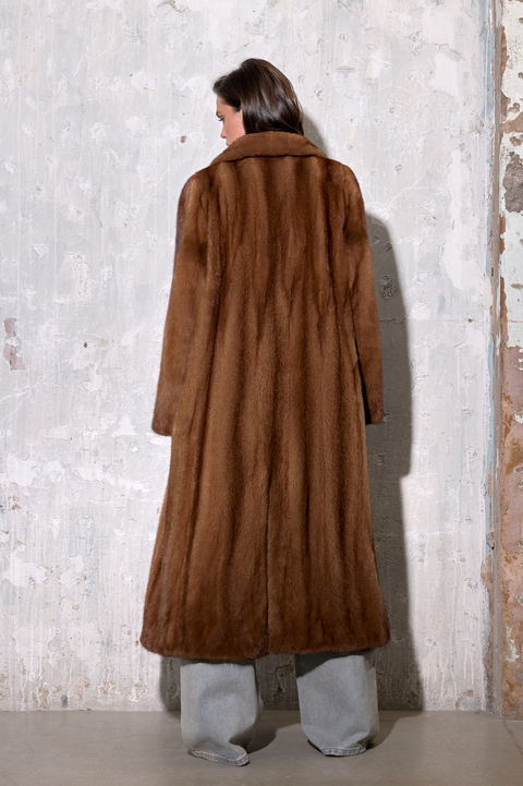 Woman wearing a Long Cognac Mink Fur Coat from the back, showcasing its luxurious and elegant design.